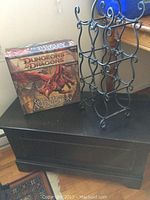 Image showing the wooden storage box, metal wine rack with curly design, and the wrapped Dungeons & Dragons Wrath of Ashardalon board game box.