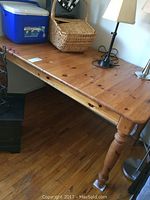 Photo of full pine table showing rectangular top and turned legs with floor and surrounding objects visible