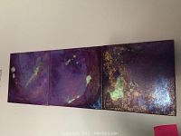 Three connected square paintings with purple and gold tones, showing the overall lot contents.