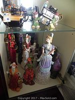 Photo showing additional ceramic figurines including one in a purple Victorian-style dress and others in diverse styles