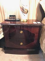 Front view of one nightstand showing two drawers, brass oval pulls, and curved scalloped front
