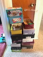 Stack of 12 shoeboxes containing various pairs of women's shoes from multiple brands.