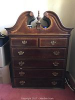 Front view of wood highboy dresser showing carved top design and drawer configuration