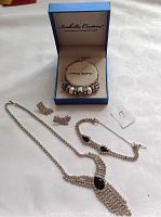 Full view of jewelry lot including bracelet in box, rhinestone necklace, rhinestone bracelet and two earrings.