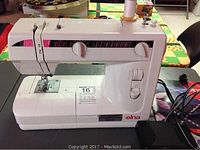 White Elna 2110-2130 sewing machine with pink-black accents and foot pedal on table, power cord visible.