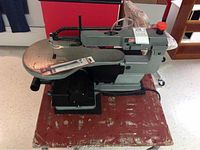 Craftsman coping saw mounted to a wooden table showing entire saw, table surface, and flexible hose attachment.