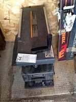 Front view of thickness planer folded with metal table surfaces and tension springs visible