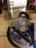 Shop-Vac wet/dry vacuum with hose and two black accessory nozzles on floor.