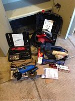 Overview of all four power tools including the Airco rotary tool, circular Skilsaw, Ryobi belt sander, and Mastercraft angle grinder with cases and accessories visible