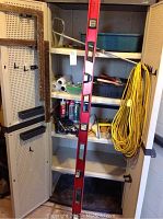 Full view of the storage cabinet showing the level, extension cord, painting tray, and various supplies inside.