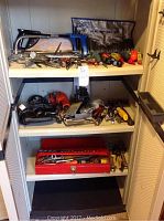 Three shelves of assorted tools and tool box organized on white shelving