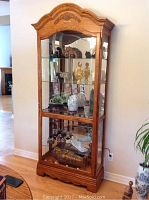 Full front view of oak curio cabinet with glass shelves and mirrored back