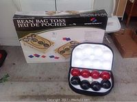 Bean bag toss game in original box and bocce ball set in open carrying case showing the balls.