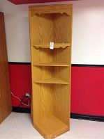 Full view of the tall corner shelving unit with four shelves and top wine glass rack in light oak finish.