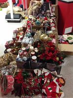 Wide view of assorted Christmas decor items including stockings, poinsettias, garlands, lights, and figurines spread out on floor