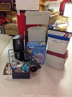 Full view of the lot showing Dr. Scholl's foot bath box, coolers, black folding chair, fan, boxes of bulbs and accessories.