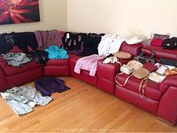 Wide shot showing many tops/sweaters and handbags arranged on red sectional sofa