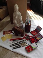 Overall lot with all items including Buddha statue, carved elephant, chopsticks, feng shui cards, jade pieces, red storage container, and decorative pendants