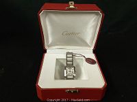 Watch displayed in open red Cartier presentation box on black surface