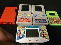 Front view of five vintage handheld electronic games with colorful button controls and cartoon-themed designs.