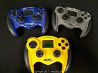 Three handheld video game controllers displayed on a black surface. Top left is blue Ice Hockey game, top right is gray Car Racing game, bottom center is yellow Baseball game.