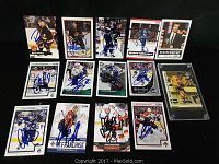 Lot of 14 autographed Vancouver Canucks hockey cards laid out, one card encased in plastic.