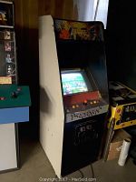 Side view of Dynamite Duke arcade game cabinet showing black and white sides and colorful artwork on top.