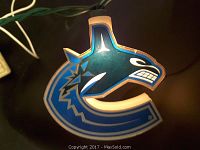 Close-up of a Vancouver Canucks logo light cover illuminated, showing blue, white, and green colors and fierce orca design.