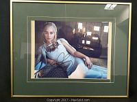 Framed signed print showing Emilia Clarke in character reclining, with autograph visible on the front.