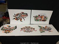 Five Native art prints by Hubert Billy arranged on a black table, showcasing various stylized animal designs in green, red, orange, black and white.