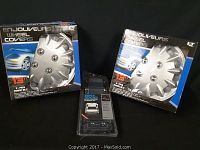 Two boxes of Enjoliveurs 13-inch wheel covers alongside a BAT 1000 backup assist sensor in sealed packaging.