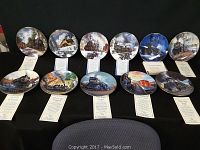 12 railroad themed collector plates displayed with certificates in front, showcasing various steam and diesel locomotives on scenic routes and at stations.