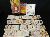 Wide shot of the lot with a large spread of Disney collector cards and three Disney character toys in packaging.