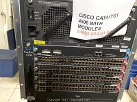 Front angled view of Cisco Catalyst 4506 chassis with five populated line card slots and one supervisor engine slot showing multiple Ethernet ports and power switch.