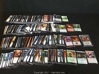 Overview photo showing a large spread of Magic the Gathering cards arranged in rows on a dark surface.