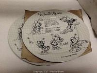 Two white ceramic round dinner plates with black sketch-style Minnie Mouse illustrations laid overlapping in photo. Plates feature grid backgrounds and various drawings and handwritten style text.