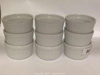 Nine white porcelain ramekins stacked in three columns of three, showing ribbed exterior and standard size.