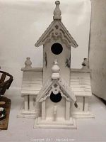 White wooden paintable birdhouse, tall with decorative trims and finials, two bird openings