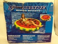 Photo of original box packaging showing a girl lying on the watermelon slice shaped Swimline float in a pool, with branding and product descriptions.