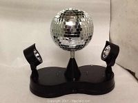 Photo of the Lumisource Mirror Madness disco ball with two attached adjustable spotlights on a black base.