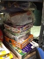Stack of seven boxed children's toys on a shelf in a dimly lit room, displaying various titles and colorful packaging.