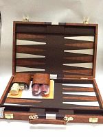 Opened brown leather backgammon case showing the playing board with contrasting light and dark triangular points. Accessories such as dice and doubling cube are contained in two brown leather pouches inside the case.