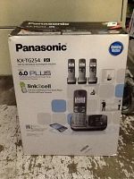 Photo of Panasonic KX-TG254 5K cordless phone system in original retail box showing product images and features.