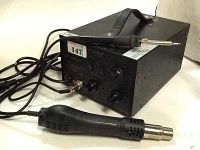 Photo showing Saike 852D+ rework station with soldering iron placed on top and hot air gun in front, connected by long cables to unit.