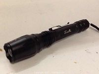 Black Ultrafire flashlight with zoomable head and clip attachment.