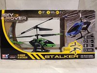 Photo of boxed Sky Rover Stalker RC helicopter showing the green and black helicopter inside and box marked with 3D, 6 channels, IR indoor control