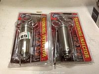 Two new-in-package Epica stainless steel seasoning injectors side by side on a white surface.