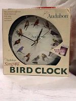 Front view of Audubon Singing Bird Clock in original packaging showcasing the clock face with twelve different North American birds and mention of included guidebook.