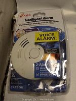 Photo shows Kidde Intelligent Alarm in original packaging, featuring label 'VOICE ALARM!' and information about combination smoke, fire, and carbon monoxide detection.