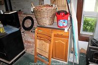 Four drawer wooden cabinet with Arborite top, assorted bins, pails, and baskets sitting around the area, part of the lot contents.